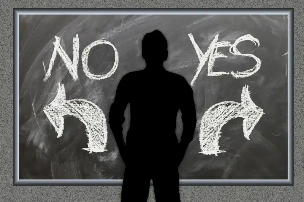 לוח גיר עם הכיתוב YES ו-NO וחיצים לכיוונים מנוגדים הממחישים דילמה והתלבטות.