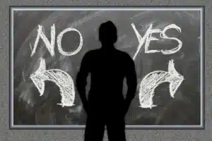 לוח גיר עם הכיתוב YES ו-NO וחיצים לכיוונים מנוגדים הממחישים דילמה והתלבטות.